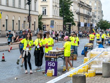 Varşova, Polonya, 9 Haziran 2024: Demir Adam triatlonu, demir adam uzun mesafe triatlon yarışları, genç Polonyalı gönüllüler eski Varşova şehir merkezinde koşuculara yardım ediyor, editoryal görüntü