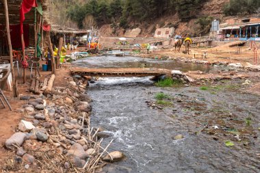 Marakeş, Fas, 10 Ocak 2024, Fas dağlarındaki dağ nehri kıyısındaki turist kafe, eski püskü rustik masalar, manzara arka planı, sonbahar yeşilliği, basit edepsiz cazibe, editoryal, görüntü
