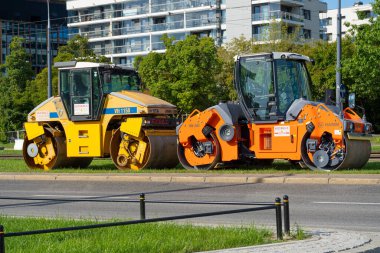 Varşova, Polonya, 19 Ekim 2023 İki asfalt silindiri park edilmiş, makineler şehir ortamında yol onarımı için hazır, modern binalar arka plan, editoryal görüntü