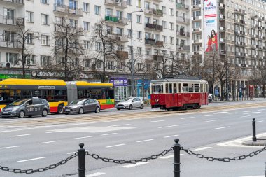 Varşova, Polonya, 25 Nisan 2023 Varşova caddesinde modern arabaları ve binaları olan klasik kırmızı tramvay. Tarihi cazibe şehir hayatı ve editörlük imajıyla buluşuyor