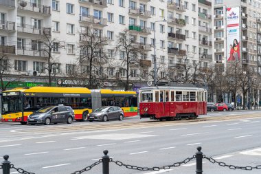 Varşova, Polonya, 25 Nisan 2023 Varşova caddesinde modern arabaları ve binaları olan klasik kırmızı tramvay. Tarihi cazibe şehir hayatı ve editörlük imajıyla buluşuyor