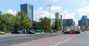 Varşova, Polonya, 9 Haziran 2024 Kırmızı spor araba. Varşova 'da kalabalık bir caddeye park edilmiş ve insanlar toplanmış. Modern binalar ve ağaçlarla şehir arkaplanı, editoryal görüntü