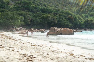 Praslin, Seyşeller, 3 Şubat 2025: Anse Lazio, Praslin, Seyşeller 'de okyanustan keyif alan turistler, arka planda dalgalar, kayalar ve tropikal yeşillikler