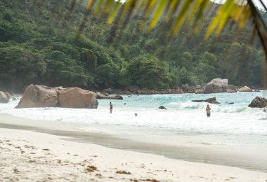 Praslin, Seyşeller, 3 Şubat 2025: Anse Lazio, Praslin, Seyşeller 'de okyanustan keyif alan turistler, arka planda dalgalar, kayalar ve tropikal yeşillikler
