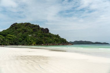 Praslin, Seyşeller, 3 Şubat 2025: Cote D 'Or Sahili, Praslin, Seyşeller, beyaz kum, turkuaz okyanus ve kayalık tepelerde yemyeşil yeşillik.