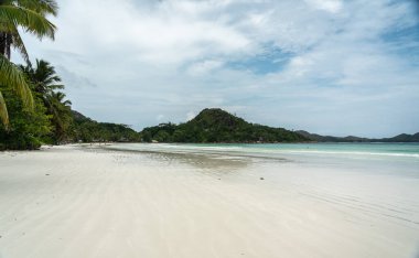 Praslin, Seyşeller, 3 Şubat 2025: Cote D 'Or Beach, Praslin, Seyşel Adaları, bulutlu gökyüzü, daha az turist ve sakin dalgalar. editoryal resim