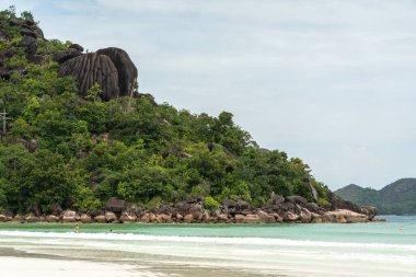 Praslin, Seyşeller, 3 Şubat 2025: Granit kayalıklar ve Cote D 'Or Sahili' ndeki verimli yeşillikler, Praslin, Seyşel Adaları 'nda insanların yüzdüğü,
