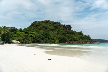 Praslin, Seyşeller, 3 Şubat 2025: Granit kayalıklar ve Cote D 'Or Sahili' ndeki verimli yeşillikler, Praslin, Seyşel Adaları 'nda insanların yüzdüğü,