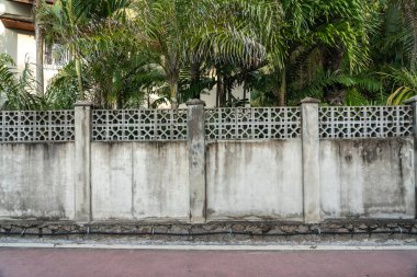 Beau Vallon, Seyşeller, 2 Şubat 2025: Arka planda yemyeşil palmiye ağaçları ve nemden dolayı siyah küfle kaplanmış eskimiş beton bir çit