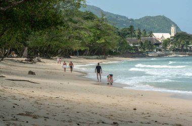 Beau Vallon, Seyşeller, 2 Şubat 2025: Turistler bulutlu bir gökyüzü görüntüsü altında Beau Vallon Sahili boyunca yürüyorlar