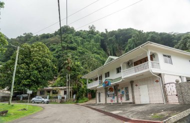 Beau Vallon, Seyşeller, 2 Şubat 2025: Seyşeller 'de bir tepe yolunda küçük yerel bir dükkan, çevresi yeşillik, evler ve tropikal bir manzara editoryal görüntüsüyle çevrili.