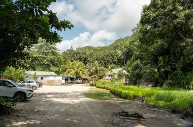 Praslin, Seyşeller, 3 Şubat 2025: Fond Ferdinand Doğa Koruma Alanı Praslin, Seyşeller 'e girin, tropik yeşillik, küçük kulübeler ve toprak park alanı editör imajı ile