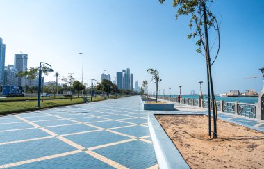 Abu Dabi, BAE, 29 Ocak 2025: Abu Dabi Corniche 'de mavi asfalt, sokak lambaları ve kıyı manzaralı geniş bir rıhtım gezisi