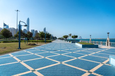 Abu Dabi, BAE, 29 Ocak 2025: Abu Dabi 'nin Corniche' sinde mavi asfalt, ağaçlar, sokak lambaları ve kıyı manzaralı geniş bir gezinti alanı