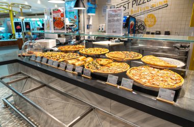 Abu Dabi, BAE, 30 Ocak 2025: Abu Dabi 'de bir havaalanı restoranında pizza büfesi, farklı malzemelerle çeşitli taze pizzalar sergileniyor.