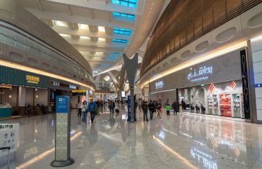 Abu Dabi, BAE, 30 Ocak 2025: Yolcular lüks dükkanlar, restoranlar ve gümrüksüz mağazalar tarafından çevrelenmiş Abu Dabi Havalimanı 'nın modern terminalinde yürüyor.