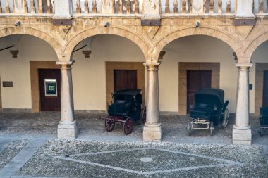 Palermo, Sicilya, İtalya, 4 Kasım 2024: Palermo, Sicilya, Sicilya 'da Palermo dei Normanni' nin avlusunda taş kemer ve sütunlar altında sergilenen antika arabalar