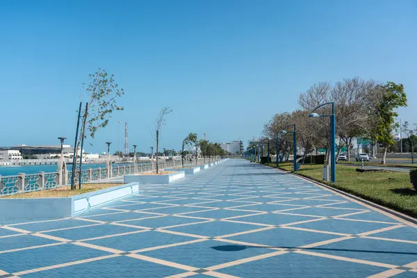 Abu Dabi, BAE, 29 Ocak 2025: Abu Dabi Corniche 'de mavi asfalt, sokak lambaları ve kıyı manzaralı geniş bir rıhtım gezisi