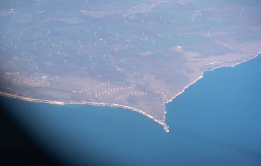 Uçak penceresi manzarası, bir sürü rüzgar türbini, deniz uçakları uçuş manzarası, uçak kabininden, mavi su ve rüzgar enerjisi üzerindeki uçak penceresi manzarası.