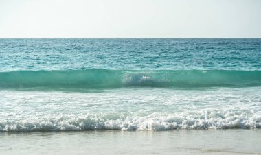 Berrak turkuaz dalgalar, sakin bir kumsalda, tropik bir ada sahilinde, Seyşeller 'in doğal deniz manzarasını gözler önüne seriyor.