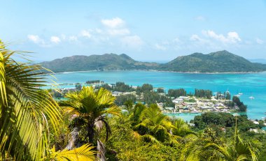 Praslin, Seyşeller tepelerinden tropik ada manzarası. Okyanusa, yemyeşil bitkilere ve açık mavi gökyüzünün altındaki uzak adalara bakıyor.