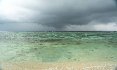 Seyşeller adaları yakınlarındaki turkuaz okyanus üzerinde kara tropik fırtına, dramatik gökyüzü, dalgalı su ve uzak kara, hava, doğa, seyahat, çevre ve fırtınalı manzara temaları için ideal