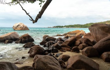 Büyük kayalıkları, turkuaz denizi, kumlu kıyıları, parlak gökyüzü altındaki uzak adaları, seyahat, tatil, doğa ve deniz manzarası temaları için ideal tropikal kıyıları