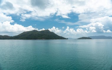 Seyşeller 'deki bir feribottan Praslin Adası' nın tropikal manzarası, berrak okyanus, mavi gökyüzü, yemyeşil tepeler ve seyahat, tatil ve keşif temaları için ideal barışçıl bir atmosfer.