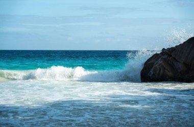Büyük tehlikeli dalgalar güzel Seyşeller sahiline çarpıyor, güçlü okyanus dalgaları, sıçramalar, mavi ufuk, tropikal çevre ve çarpıcı bir deniz manzarası yaratıyor.