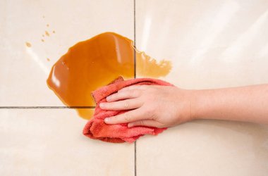 Dökülmüş kahve, kadın fayanslı zemindeki kahve lekesini siliyor, dökülen fincanla karışık sızıntı, dökülen kahverengi içki temizliği.