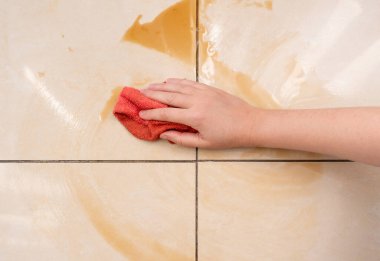 Dökülmüş kahve, kadın fayanslı zemindeki kahve lekesini siliyor, dökülen fincanla karışık sızıntı, dökülen kahverengi içki temizliği.