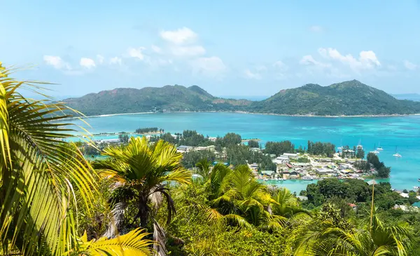 Praslin, Seyşeller tepelerinden tropik ada manzarası. Okyanusa, yemyeşil bitkilere ve açık mavi gökyüzünün altındaki uzak adalara bakıyor.