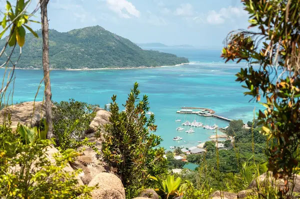Seyşeller 'deki Hint Okyanusu' nun tekneleri, tropikal ormanları ve turkuaz sularıyla Baie Sainte Anne 'e bakan Praslin Adası' ndaki tepenin manzarası.