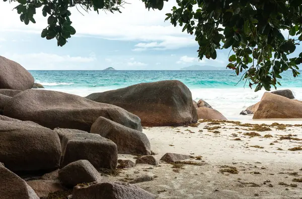 Büyük kaya parçaları, turkuaz okyanus dalgaları, uzak adalar ve Praslin, Seyşeller 'deki yemyeşil bitki örtüsü seyahat, turizm ve doğa temaları için idealdir.