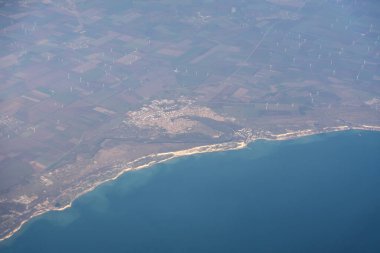 Uçak penceresi manzarası, bir sürü rüzgar türbini, deniz uçakları uçuş manzarası, uçak kabininden, mavi su ve rüzgar enerjisi üzerindeki uçak penceresi manzarası.