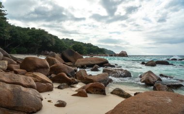 Büyük kayalıkları, turkuaz denizi, kumlu kıyıları, parlak gökyüzü altındaki uzak adaları, seyahat, tatil, doğa ve deniz manzarası temaları için ideal tropikal kıyıları