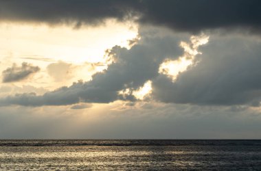 Sakin denizin üzerindeki bulut katmanları, Seyşeller 'deki La Digue adası yakınlarında alacakaranlıkta yumuşak ışığı yansıtır. Anse Kaynak d 'Argent kıyı şeridinden okyanus yüzeyinin huzurlu manzarası