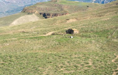 Sicilya kırsalındaki çimenli tepelerde terk edilmiş bir kır evi. Etrafı tarlalar ve tarlalarla çevrili bir kır evi.
