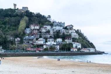 San Sebastian, İspanya, 17 Nisan 2024: Evler San Sebastian plajı yakınındaki yamaçta yükseliyor, şehir yaşamını manzaralı kıyı arazisiyle harmanlıyor, editoryal görüntü