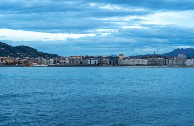 San Sebastian, İspanya, 17 Nisan 2024: San Sebastian rıhtım silueti alacakaranlıkta sakin körfez sularına yansıyan şehir ışıklarıyla, editoryal görüntü