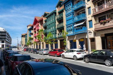 Zumaia, İspanya, 4 Nisan 2024: Balkonlu renkli cepheler Zumaia, Bask Ülkesi 'nde güneşli bir cadde, park halindeki arabalar ve yürüyen insanlar, editoryal görüntü
