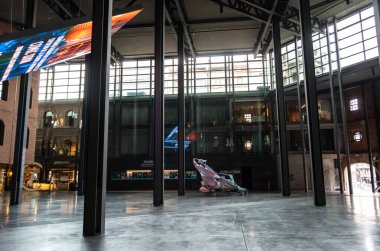 Bilbao, İspanya, 4 Nisan 2024: Bilbao 'da cam duvarları, çelik kolonları ve sanat eserleri olan bir müzenin içi. wal, editoryal resim üzerine sergi posterleri ve dijital ekran
