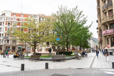 Bilbao, İspanya, 4 Nisan 2024: Bilbao 'daki Jardines de Albia Meydanı' nda sıraları, ağaçları ve aslan çeşmeleri var. Şehir merkezindeki fayanslı yolda yürüyen insanlar, editoryal görüntü
