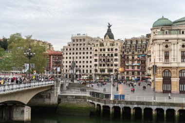Bilbao, İspanya, 4 Nisan 2024: Bilbao 'daki Arenal Köprüsü ve Arriaga Plaza' nın tarihi binaları, nehri ve yürüyen yayaları ile birlikte sinema, editoryal görüntü