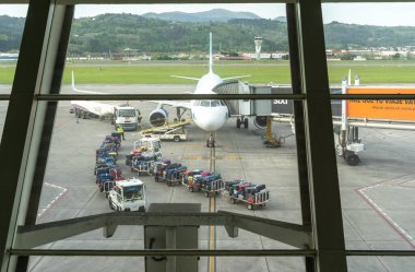 Bilbao, İspanya, 4 Nisan 2024: Bilbao Havaalanı 'nın kapısındaki uçak pistte bagaj vagonları, yakıt kamyonu ve jet köprüsü ile servis ediliyor