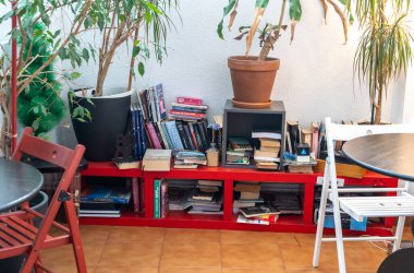 Bilbao, İspanya, 4 Nisan 2024: Bilbao Akelarre Hostel 'in ortak alanında karışık kitaplar ve saksılarla dolu kitaplık, sandalye ve tabloların yanında, editoryal resim