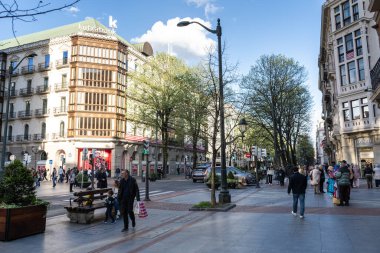 Bilbao, İspanya, 4 Nisan 2024: Kutxabank binası ve Bilbao 'daki Gran Via geçidinde yayalar, bahar ağaçları ve sağdaki Oysho mağazası, editoryal görüntü
