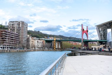 Bilbao, İspanya, 4 Nisan 2024: La Salve Köprüsü, Bilbao, Bask Bölgesi 'ndeki Guggenheim Müzesi giriş kulesinin yanındaki kırmızı kemerli bina, editoryal görüntü