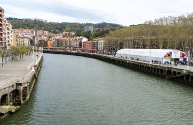 Bilbao, İspanya, 28 Mart 2024: Büyük olay çadırı ve renkli binalar Bilbao 'daki Nervion Nehri' ne bağlıdır. Nehir kenarındaki gezinti alanı, uluslararası bayraklı ve editoryal imajlı bir halk festivaline ev sahipliği yapıyor.