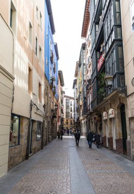 Bilbao, İspanya, 28 Mart 2024: Bilbao 'da renkli cepheleri ve balkonları olan dar yaya sokağı. Yerel halk ve turistler, editoryal bir imajla tarihi yerleşim bölgesinde yürüyor